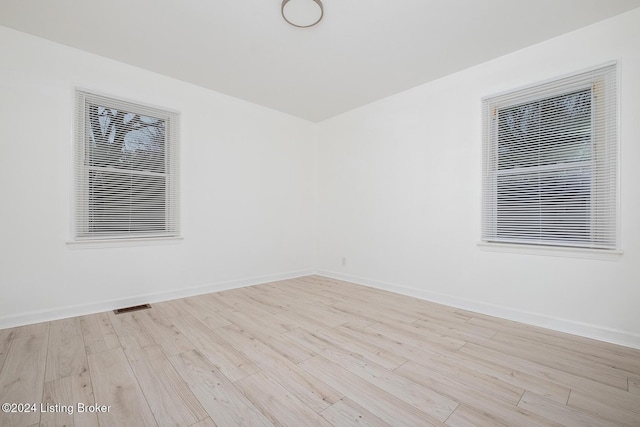 unfurnished room with light wood-type flooring, visible vents, and baseboards