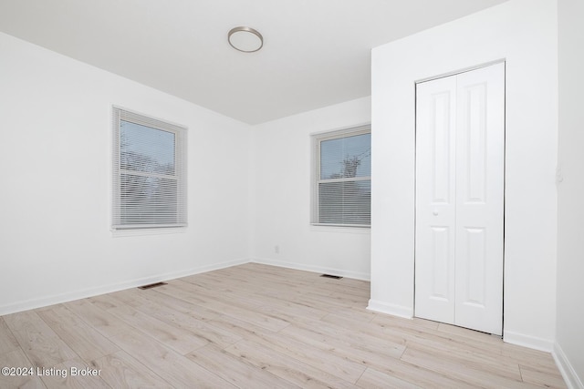 unfurnished bedroom featuring visible vents, a closet, light wood-style flooring, and baseboards