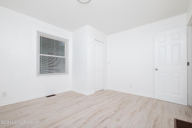 empty room featuring wood finished floors, visible vents, and baseboards