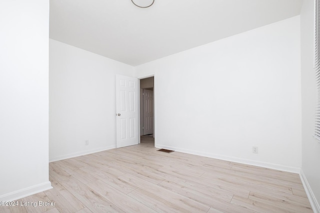 spare room featuring light wood finished floors, baseboards, and visible vents