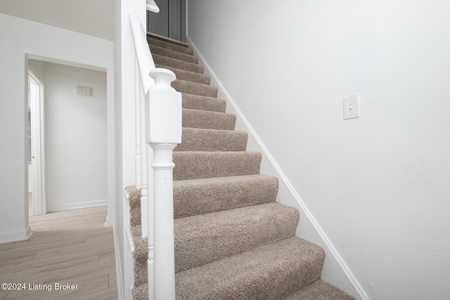 stairway with wood finished floors and baseboards