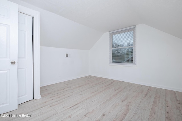 additional living space featuring lofted ceiling, baseboards, visible vents, and wood finished floors