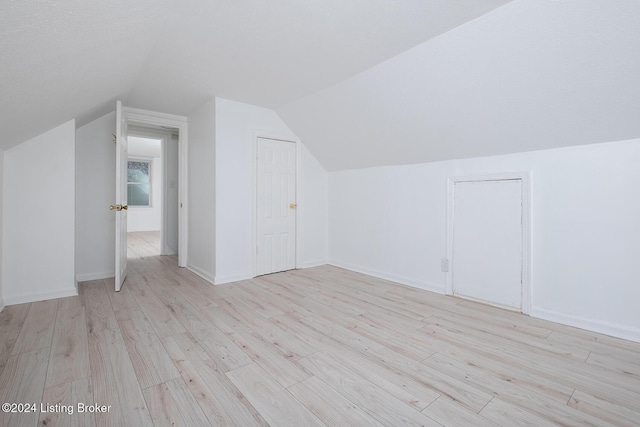 additional living space with lofted ceiling, light wood-style floors, and baseboards