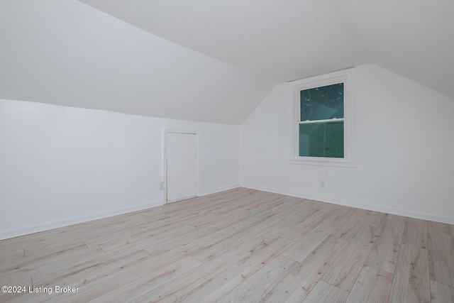 bonus room featuring light wood finished floors and vaulted ceiling