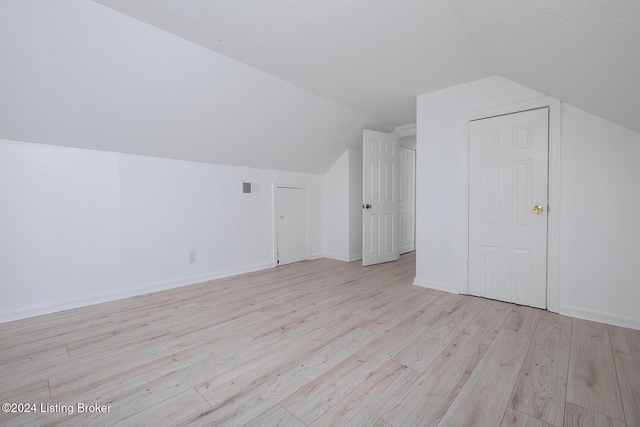 additional living space with lofted ceiling, light wood-style floors, baseboards, and visible vents