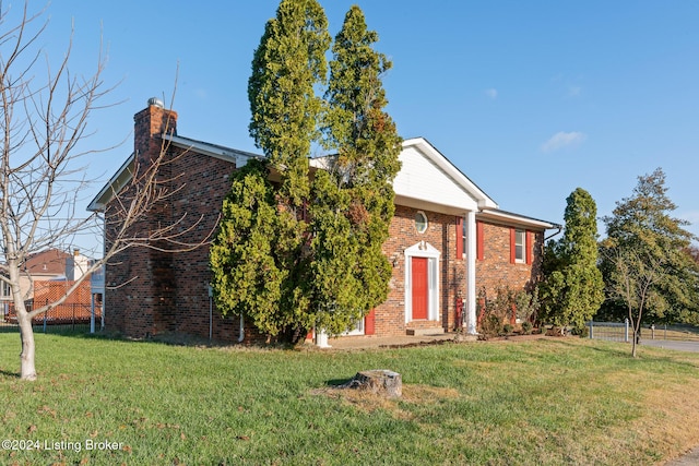 view of front facade with a chimney, a front yard, fence, and brick siding