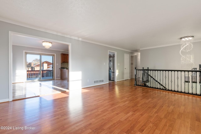 empty room with baseboards, light wood-style flooring, visible vents, and a notable chandelier