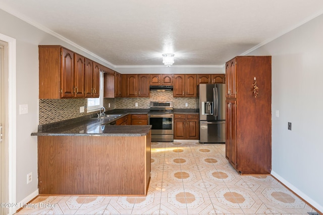 kitchen with stainless steel appliances, dark countertops, a sink, and a peninsula