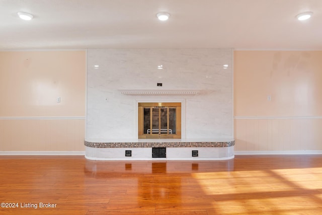 unfurnished living room featuring a wainscoted wall, wood finished floors, and a high end fireplace