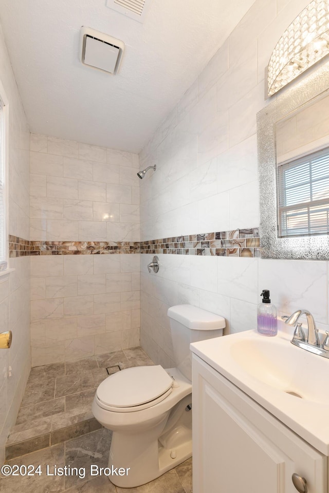 bathroom featuring tile walls, toilet, a tile shower, vanity, and backsplash