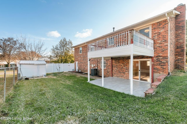 back of house with an outbuilding, a fenced backyard, brick siding, a yard, and a patio area