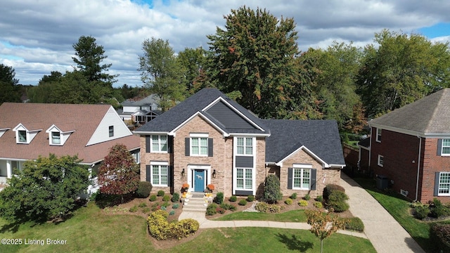 view of front facade featuring brick siding, central AC unit, a shingled roof, and a front yard