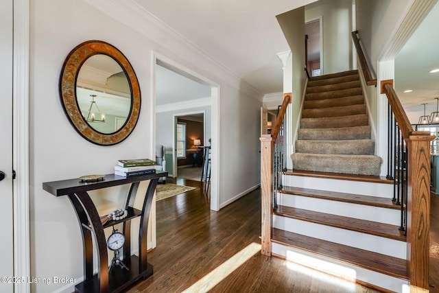 stairway with baseboards, crown molding, a chandelier, and wood finished floors