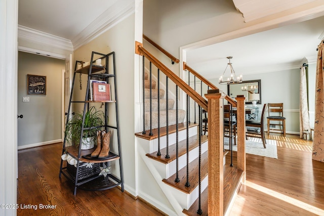 stairs with a notable chandelier, baseboards, wood finished floors, and crown molding