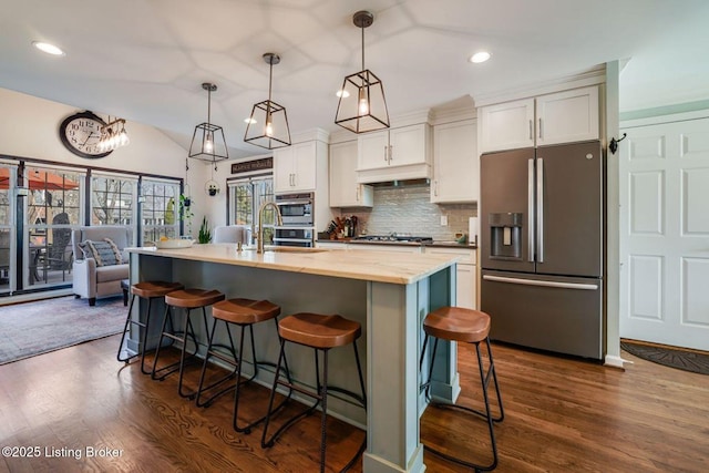 kitchen featuring white cabinets, lofted ceiling, stainless steel appliances, under cabinet range hood, and a sink