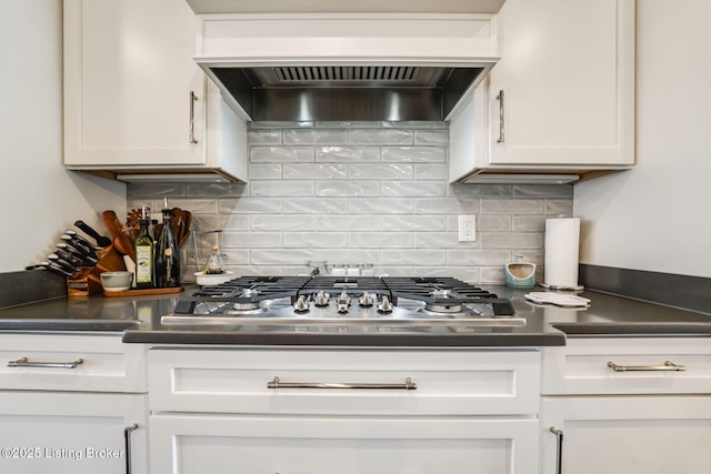 kitchen with tasteful backsplash, dark countertops, custom exhaust hood, white cabinetry, and stainless steel gas cooktop