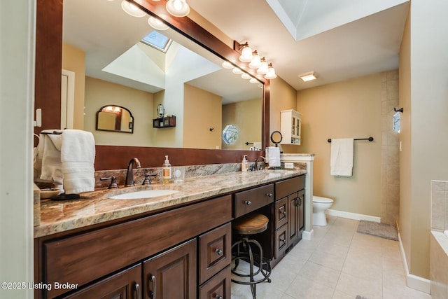 full bath featuring a skylight, double vanity, toilet, a sink, and tile patterned floors