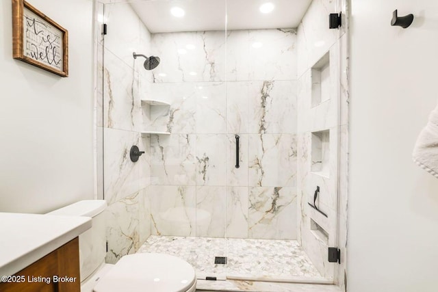 bathroom featuring vanity, a shower stall, and toilet