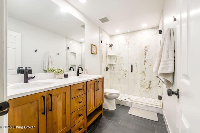 bathroom featuring toilet, a sink, a marble finish shower, and double vanity