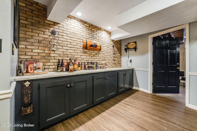 bar with a bar, light wood finished floors, and baseboards