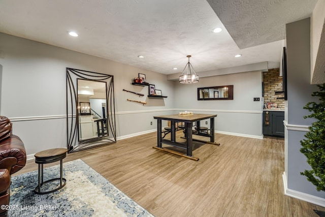 dining area featuring light wood-style flooring, baseboards, a textured ceiling, and recessed lighting