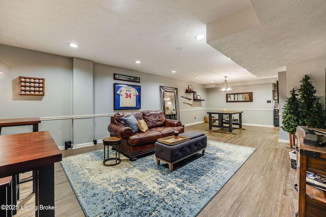 living room with a textured ceiling, light wood-type flooring, baseboards, and recessed lighting