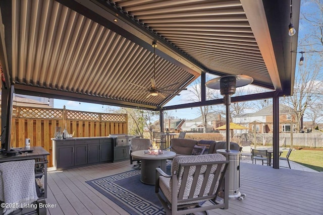 wooden terrace featuring ceiling fan, fence, a fire pit, and a grill