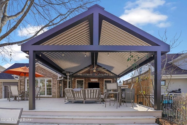 exterior space featuring outdoor dining area, brick siding, a gazebo, fence, and a wooden deck