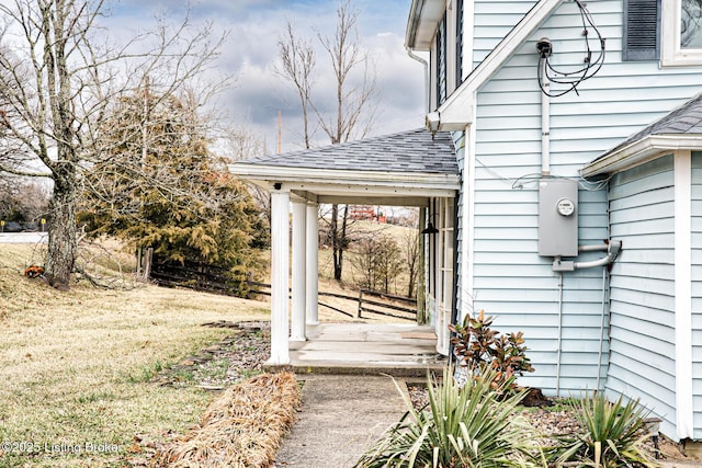 entrance to property featuring a yard and roof with shingles