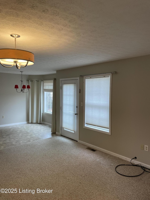 spare room with baseboards, visible vents, a textured ceiling, and light colored carpet