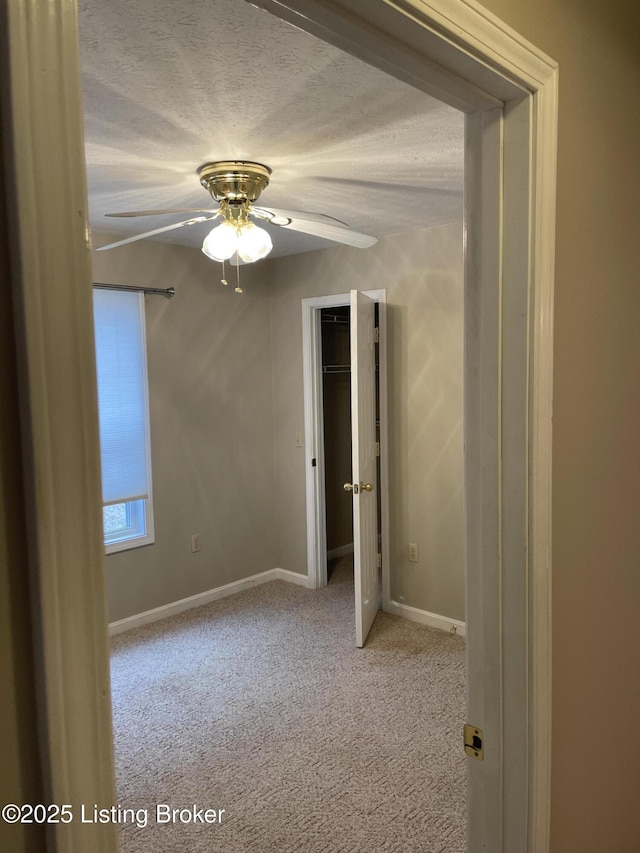 unfurnished bedroom with a textured ceiling, carpet, a ceiling fan, and baseboards