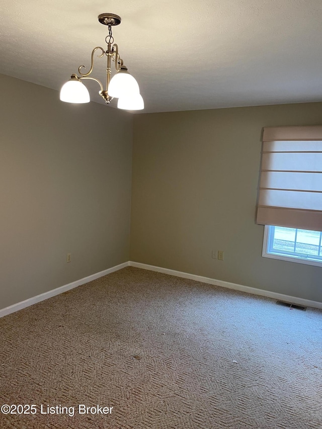 carpeted spare room featuring visible vents, baseboards, and a chandelier