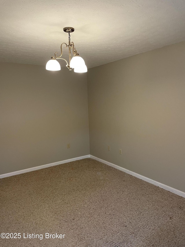 spare room with a notable chandelier, a textured ceiling, and baseboards