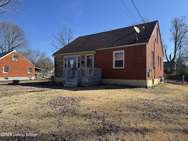 view of front of home with brick siding, a shingled roof, and fence