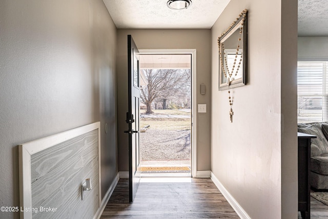 doorway featuring a textured ceiling, wood finished floors, and baseboards