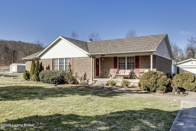 single story home with a porch, brick siding, an outdoor structure, roof with shingles, and a front lawn