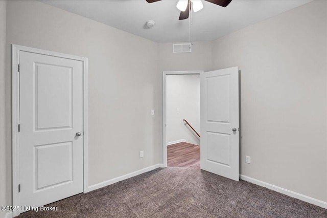 unfurnished bedroom with ceiling fan, dark carpet, visible vents, and baseboards