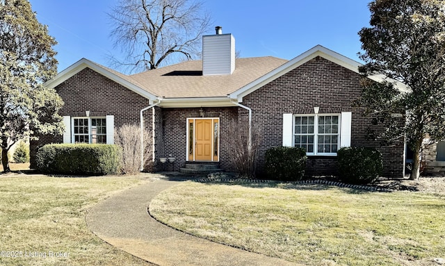 ranch-style house featuring brick siding, a chimney, a front lawn, and a shingled roof