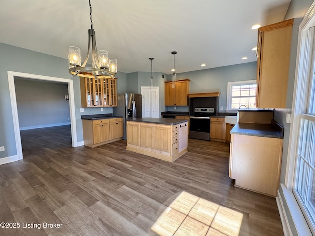 kitchen featuring dark countertops, a kitchen island, glass insert cabinets, appliances with stainless steel finishes, and dark wood-style flooring