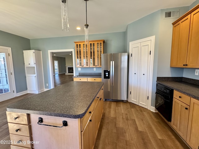 kitchen featuring visible vents, dark wood-style flooring, oven, dark countertops, and stainless steel fridge