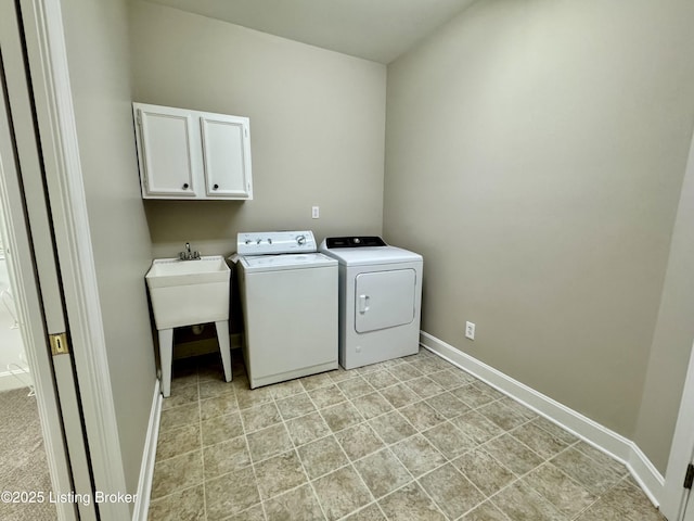 clothes washing area featuring separate washer and dryer, cabinet space, and baseboards