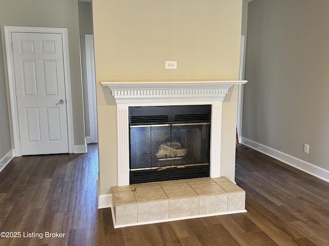 details with a tiled fireplace, baseboards, and wood finished floors