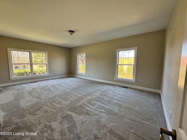 carpeted spare room featuring visible vents and baseboards