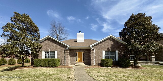 single story home featuring brick siding, a chimney, a front lawn, and a shingled roof