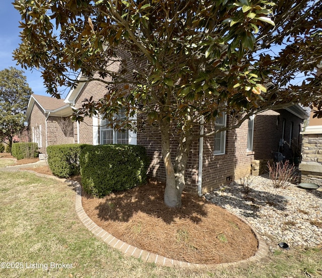 view of home's exterior with brick siding and a lawn