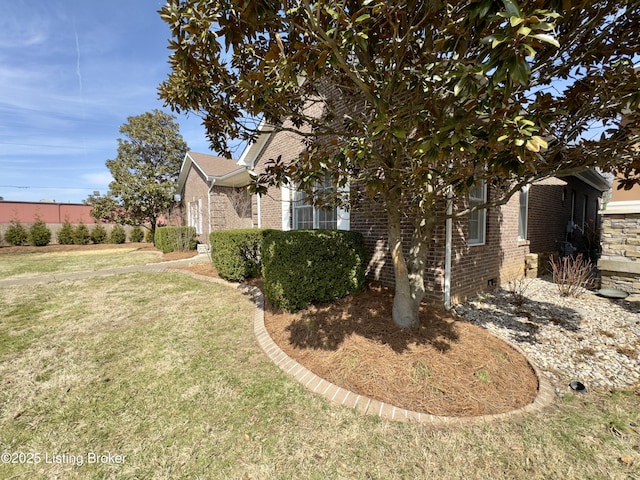 view of side of home featuring brick siding and a yard