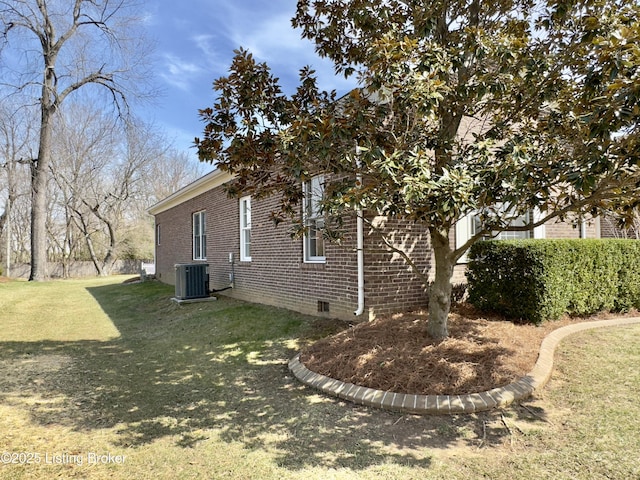 view of side of home featuring brick siding, crawl space, a lawn, and central AC