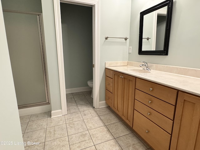 bathroom featuring tile patterned flooring, a shower stall, baseboards, toilet, and vanity