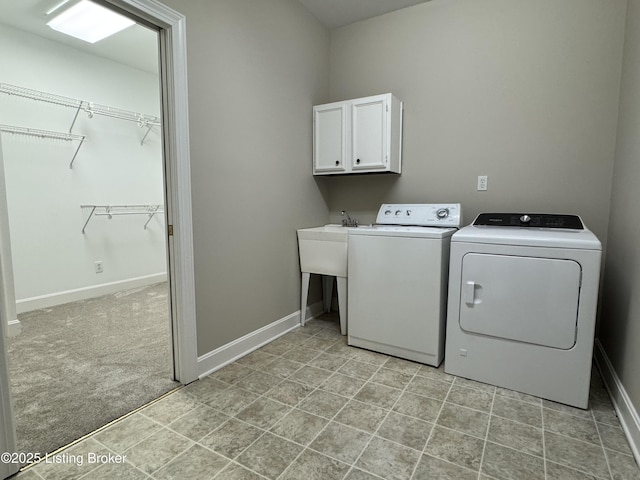 laundry room with washing machine and dryer, cabinet space, light colored carpet, and baseboards