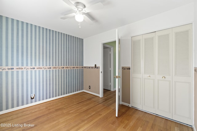 3004 Brownsboro Vista Dr, Louisville, KY 40242 - unfurnished bedroom with wallpapered walls, an accent wall, baseboards, wood finished floors, and a closet